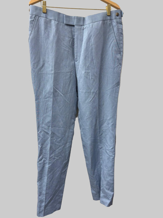 Light blue pants hanging on a hanger against a white wall.