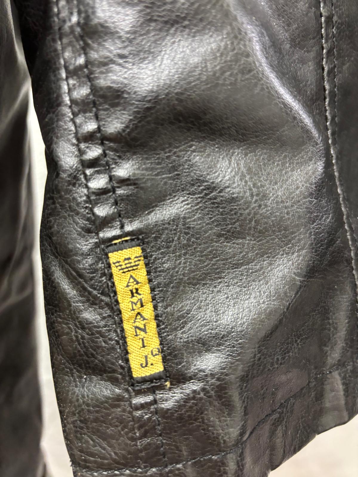 Close-up of a black leather jacket with a yellow Armani label.
